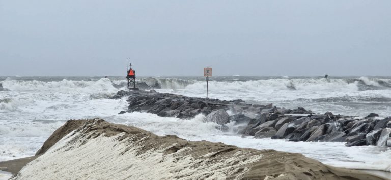 Storm surge washing over the sand toward the Rudee Inlet jetty during a nor’easter