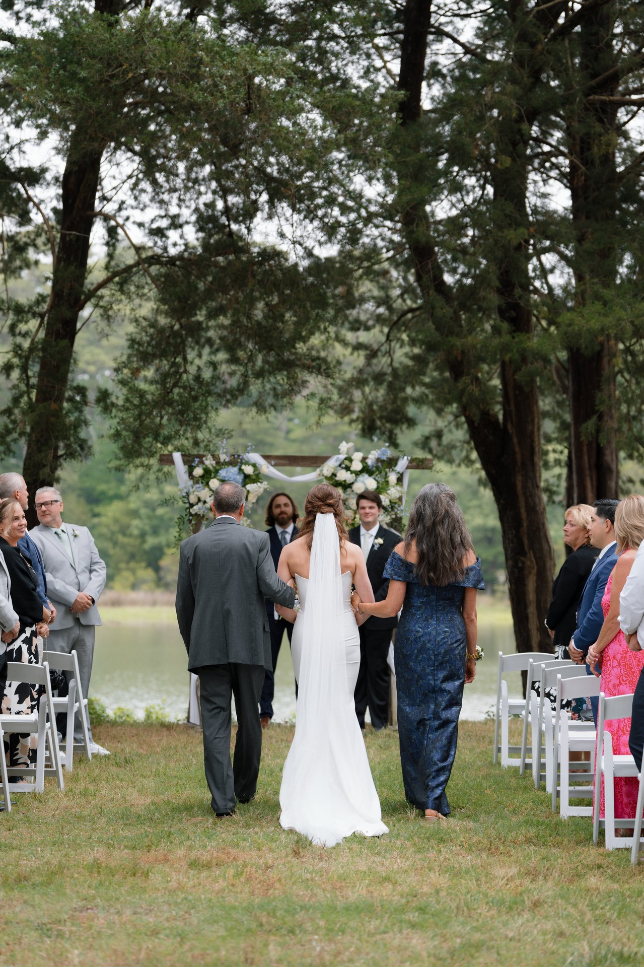 The wedding party walking down the aisle toward the water The wedding party walking down the aisle toward the water