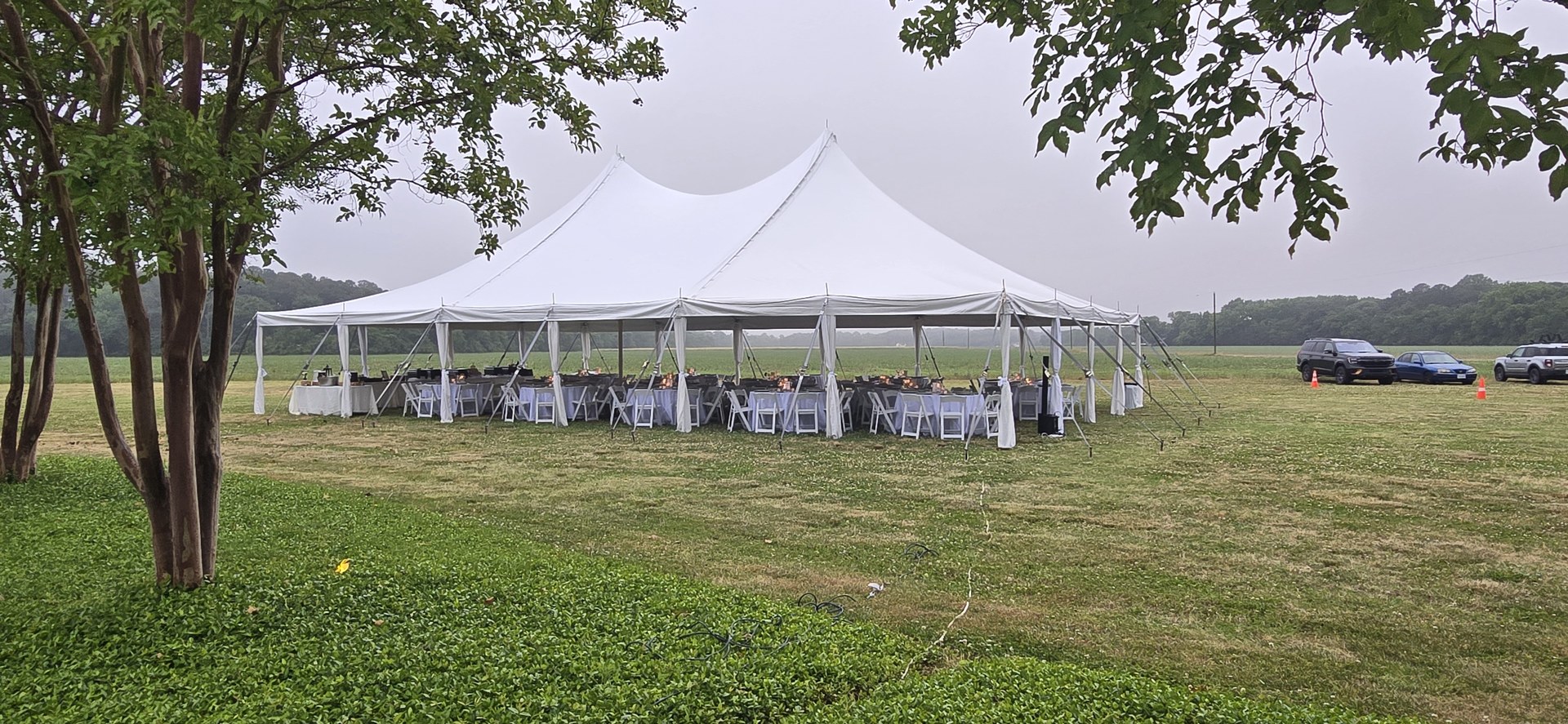 Reception tables set under a white tent Reception tables set under a white tent