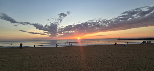 Sunrise clouds at the Virginia Beach oceanfront with people on the sand taking in the view