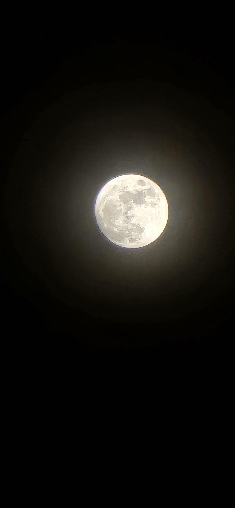 A full moon glowing bright against a dark night sky.