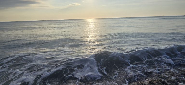 First light stretching across still ocean water at the Virginia Beach oceanfront