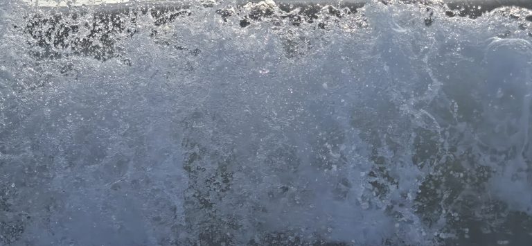 Close-up of a breaking wave, spray and droplets catching the morning light at the Virginia Beach oceanfront